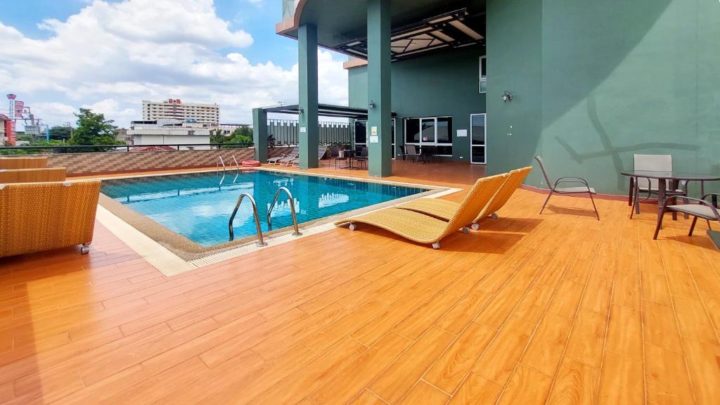 A rooftop pool deck with loungers, outdoor seating, and city views.