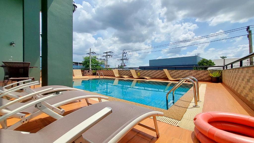 A rooftop pool with loungers, a ladder and views toward surrounding buildings and sky.