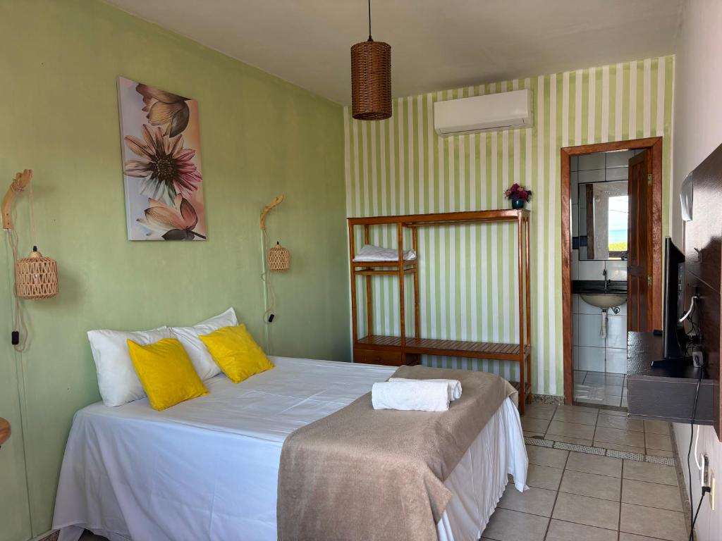 a bedroom with a large white bed with yellow pillows at Pequena Sereia Guriri in São Mateus