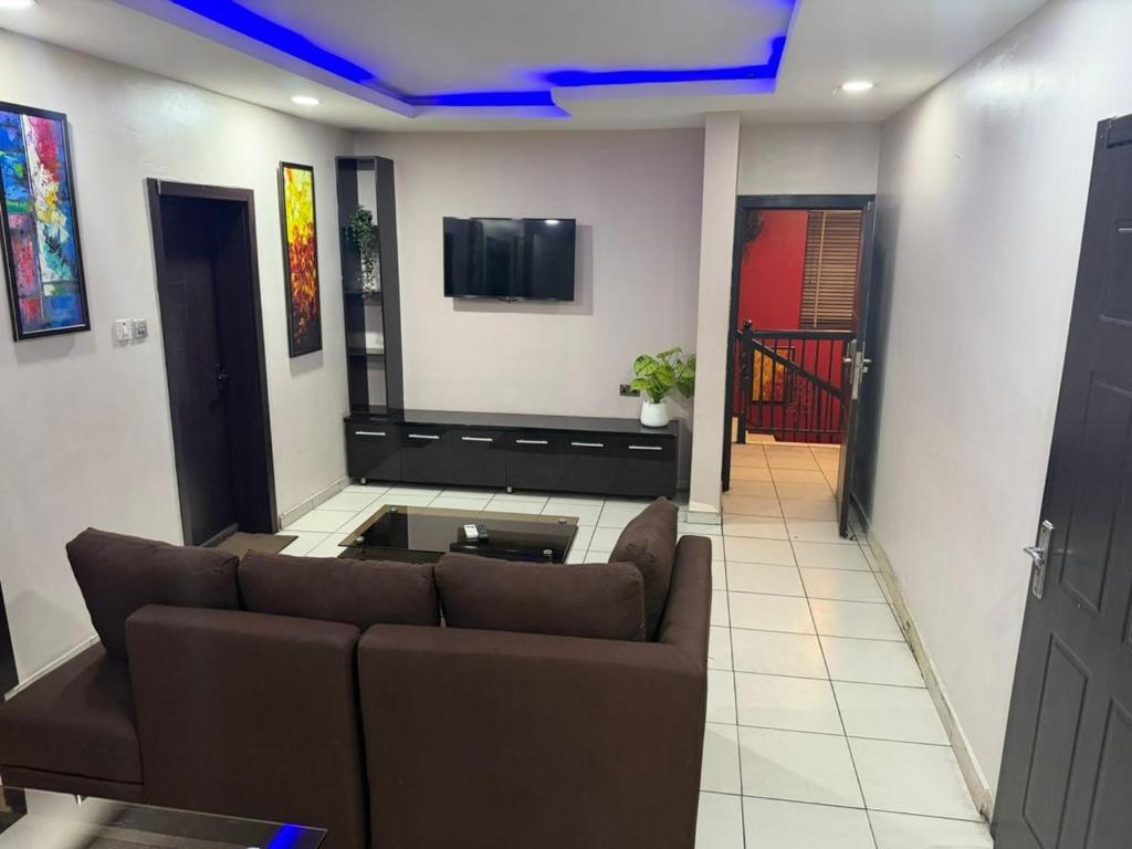 a living room with a couch and a tv at NO 95 Suites LEKKI PHASE 1 in Ilado