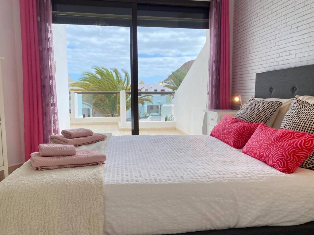 a bedroom with a large bed with pink pillows on it at Casa Candy. Piscina, Mar y Paz. in Tuineje