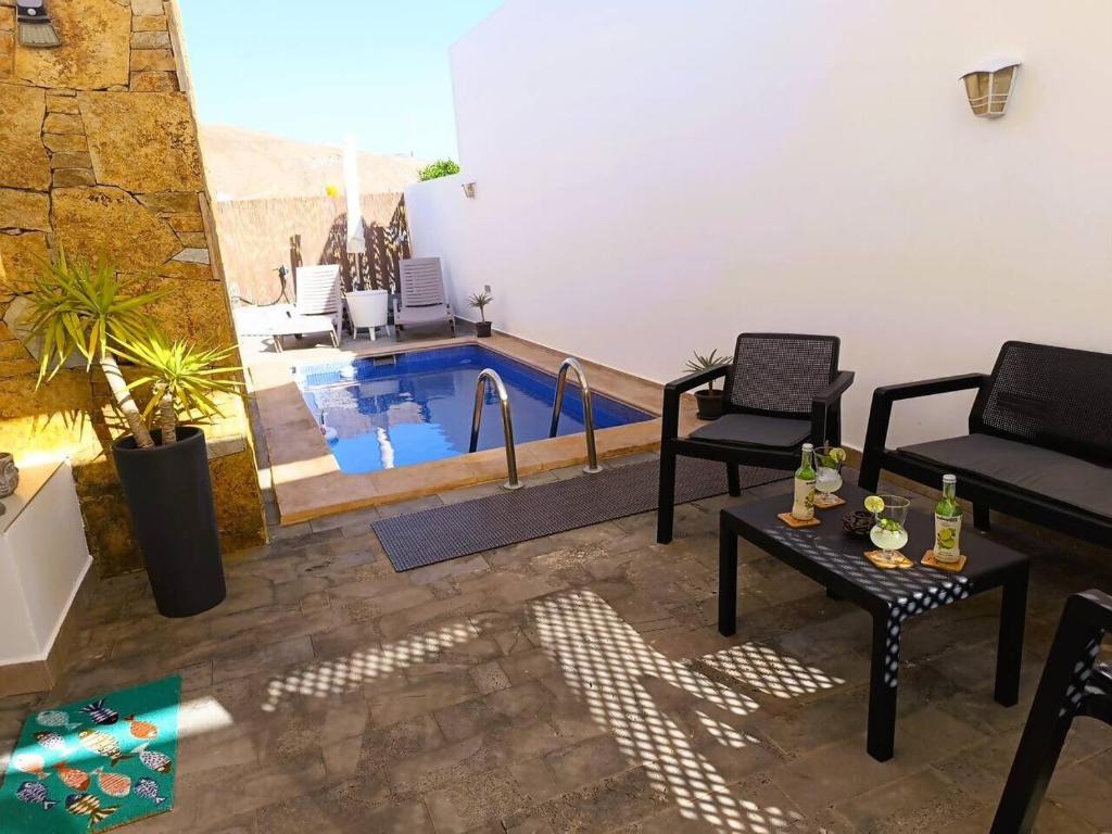 a living room with a pool with two chairs and a table at Villa Majada Del Aceitun in Gran Tarajal