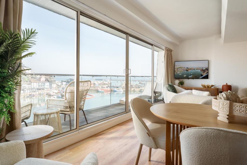 a living room with a table and chairs and a large window at Quayside Apartments, Brixham in Brixham