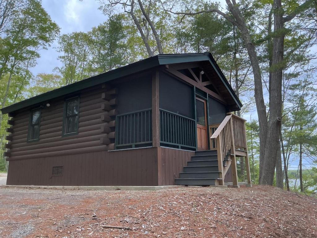a cabin in the woods with a porch and stairs at Rivers Edge Cabins - Tranquil Nook in Cushing