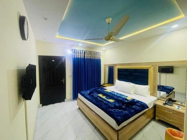 a bedroom with a large bed with a blue blanket at Lasani view Guest House in Lahore