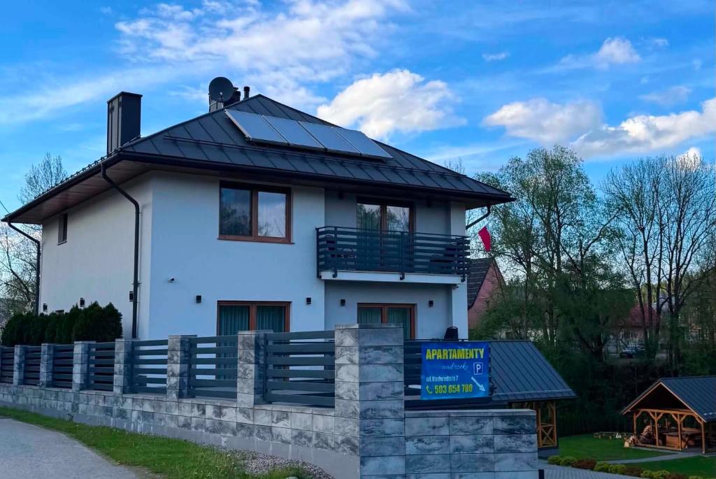 a white house with a black roof at Apartamenty Nad Rzeką z balią in Kacwin