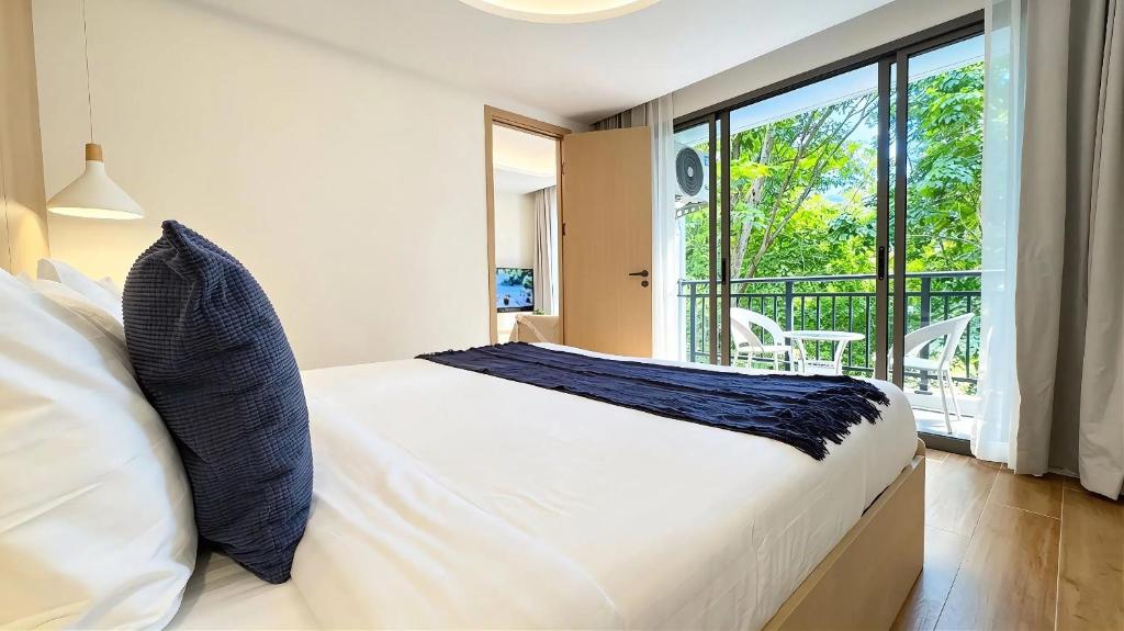 a bedroom with a white bed and a balcony at Peaceful Fantasia Condo Kamala in Surin Beach