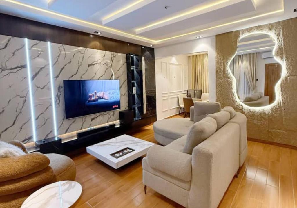 a living room with a couch and a large screen tv at Mega Luxury Apartment in Asagba