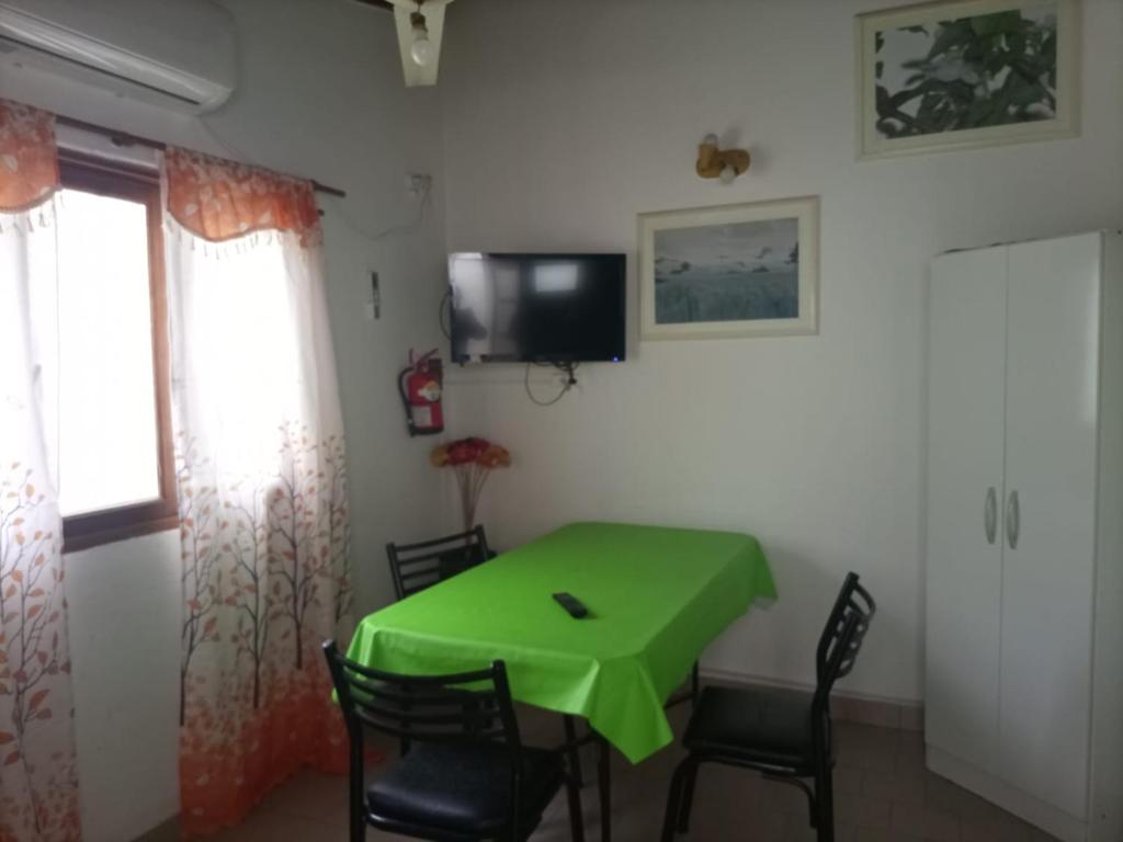 a dining room with a green table and chairs at Las Grutas Centro alojamiento in Las Grutas