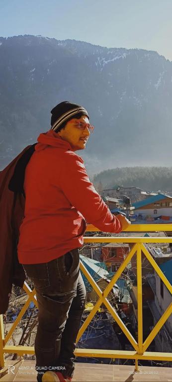 a man standing on top of a yellow railing at UpClimb Longstay for bus or taxi only guests in Manāli