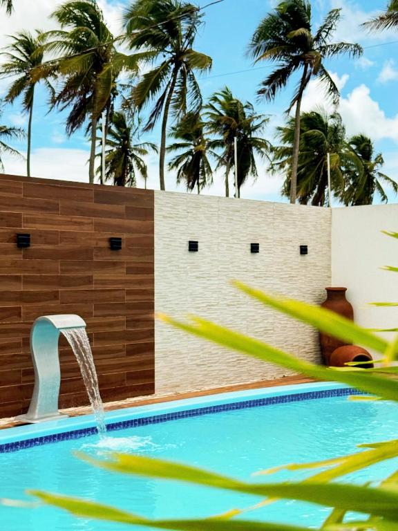 a swimming pool with a waterfall and palm trees at Casa Quebec - Apartamentos in São Miguel do Gostoso