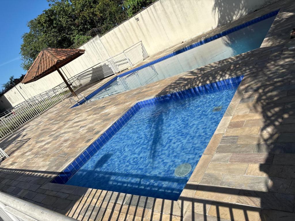 a blue swimming pool with a fence and an umbrella at Lazer Oceanos in São Vicente
