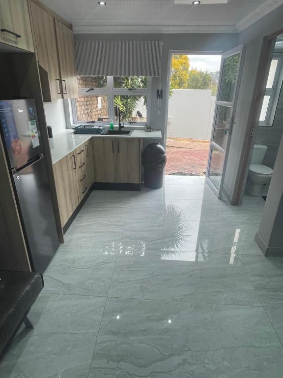 a kitchen with a refrigerator and an open door at Abijah Ridgeview Studios in Roodepoort