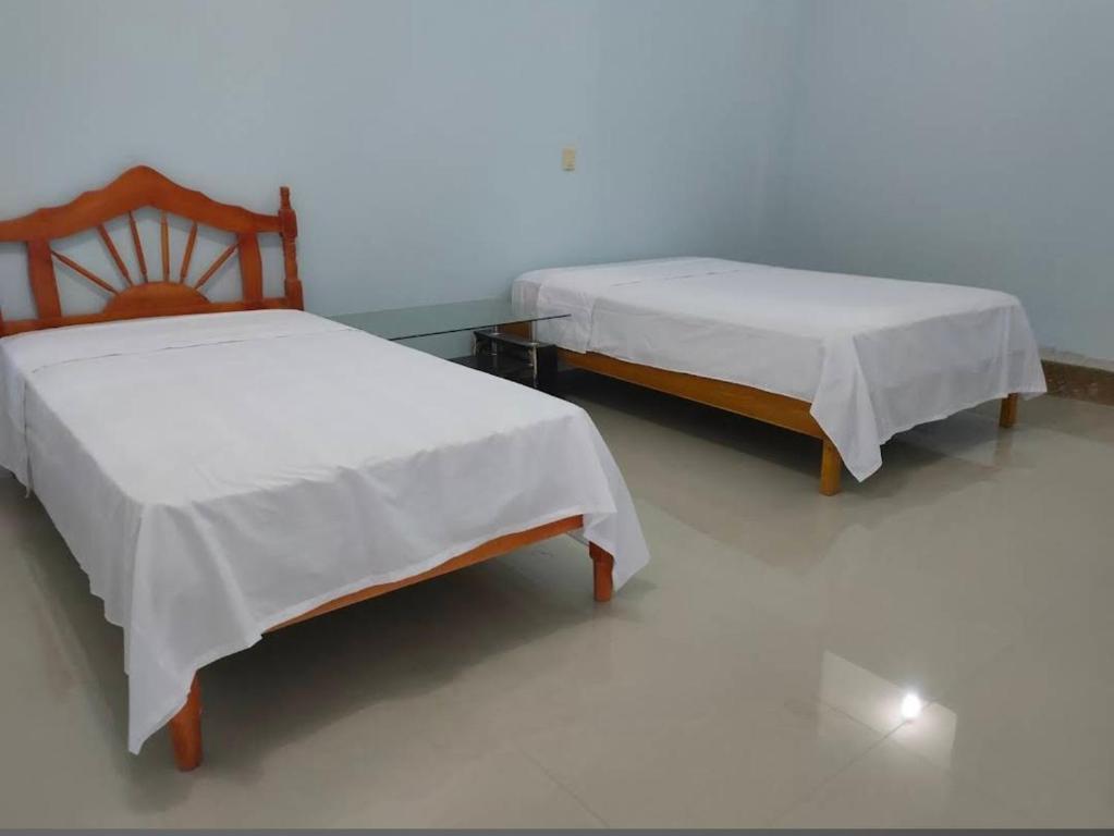 two beds sitting next to each other in a room at Hostal El Bosque in Pedernales