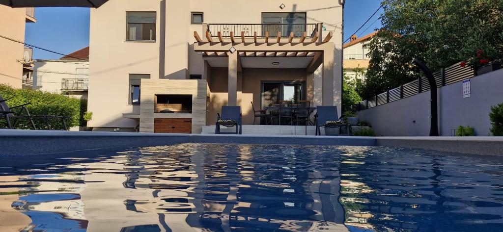 a swimming pool in front of a house at Holiday house Vito Zadar in Zadar