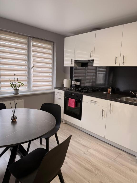 a kitchen with white cabinets and a table and chairs at Apartment Ventos 55 in Mažeikiai