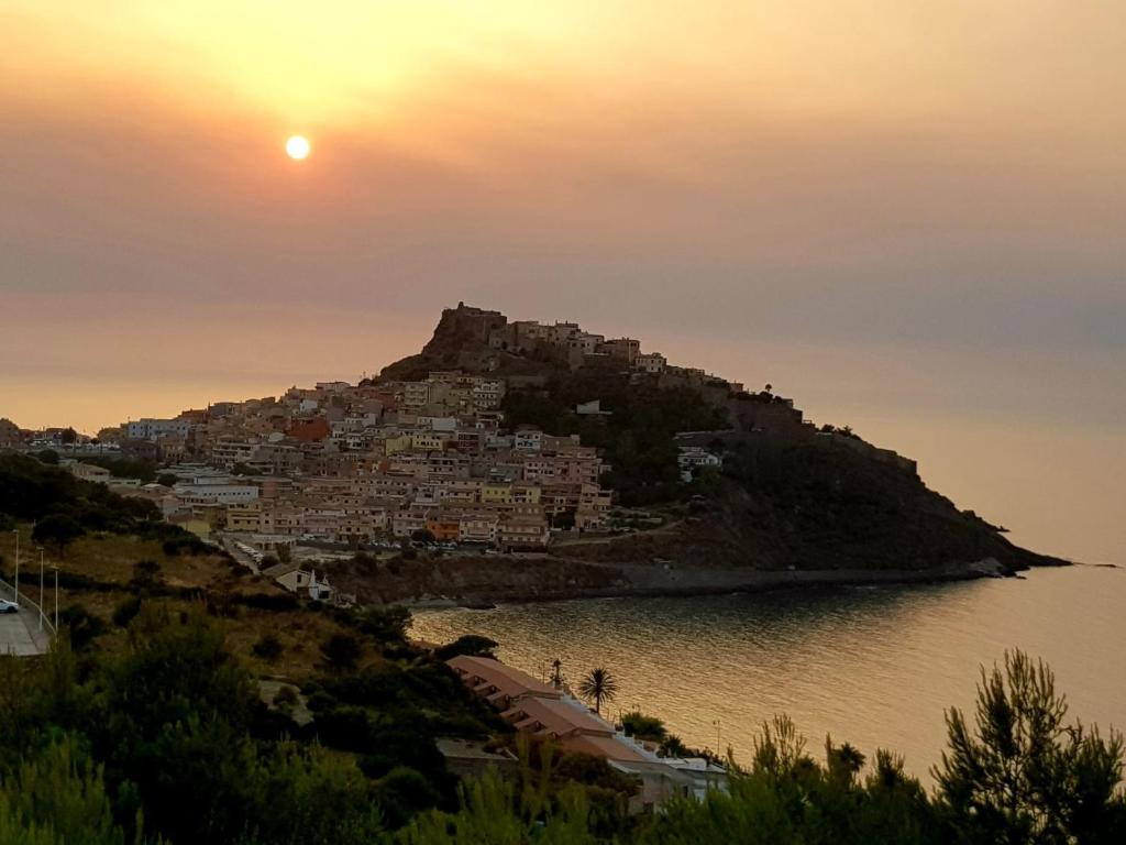 a city on a hill with the sun setting at Centralissimo Charlie Beach in Castelsardo