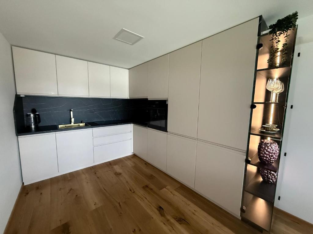 a kitchen with white cabinets and a wooden floor at Villa Vita - MELANI in Slovenj Gradec