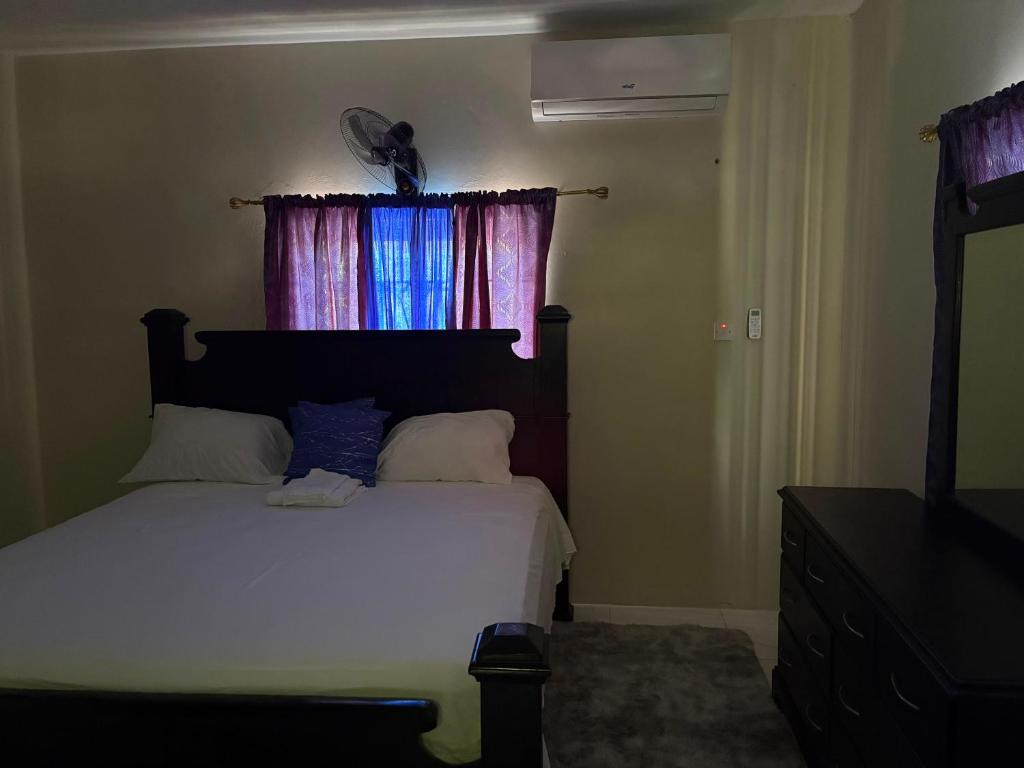 a bedroom with a white bed and a window at Stays at Global Dreams in Beckford Town