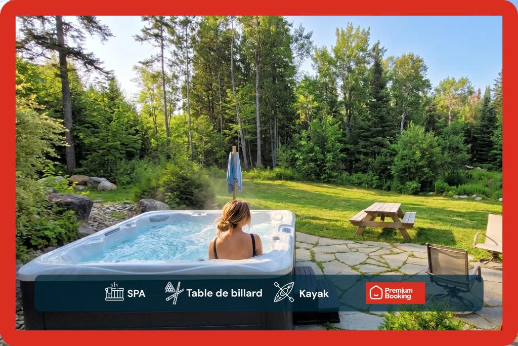a woman sitting in a hot tub in a yard at Fiddler Lake 72 with Private spa, pool table & Pool in Mille-Isles