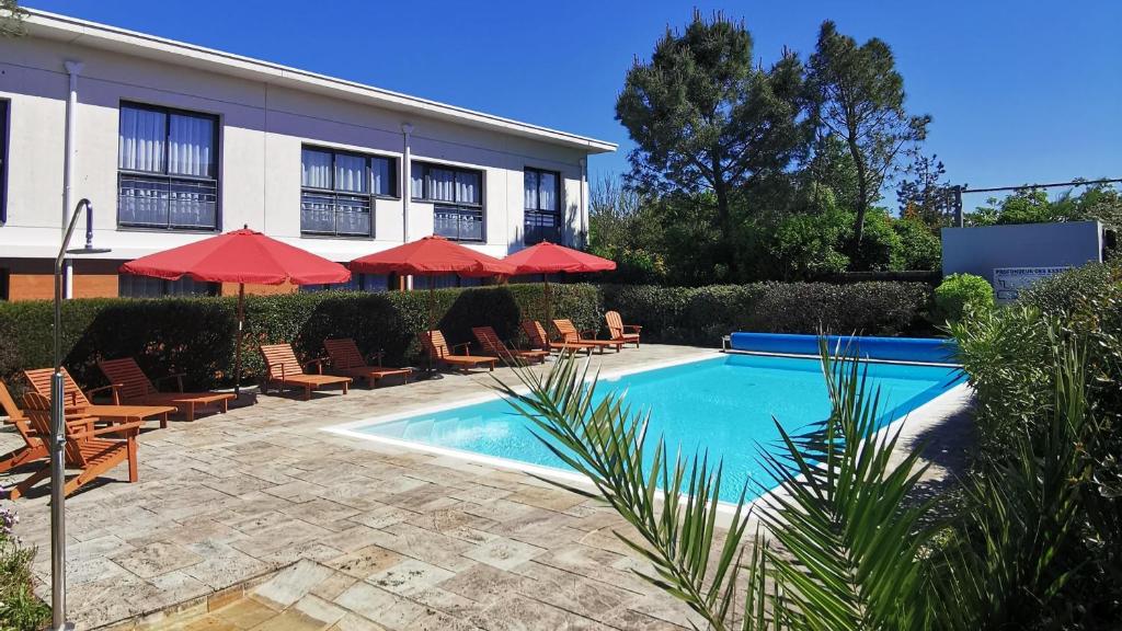 a hotel with a swimming pool with chairs and umbrellas at Best Western Hôtel De La Cité & Spa in Guérande