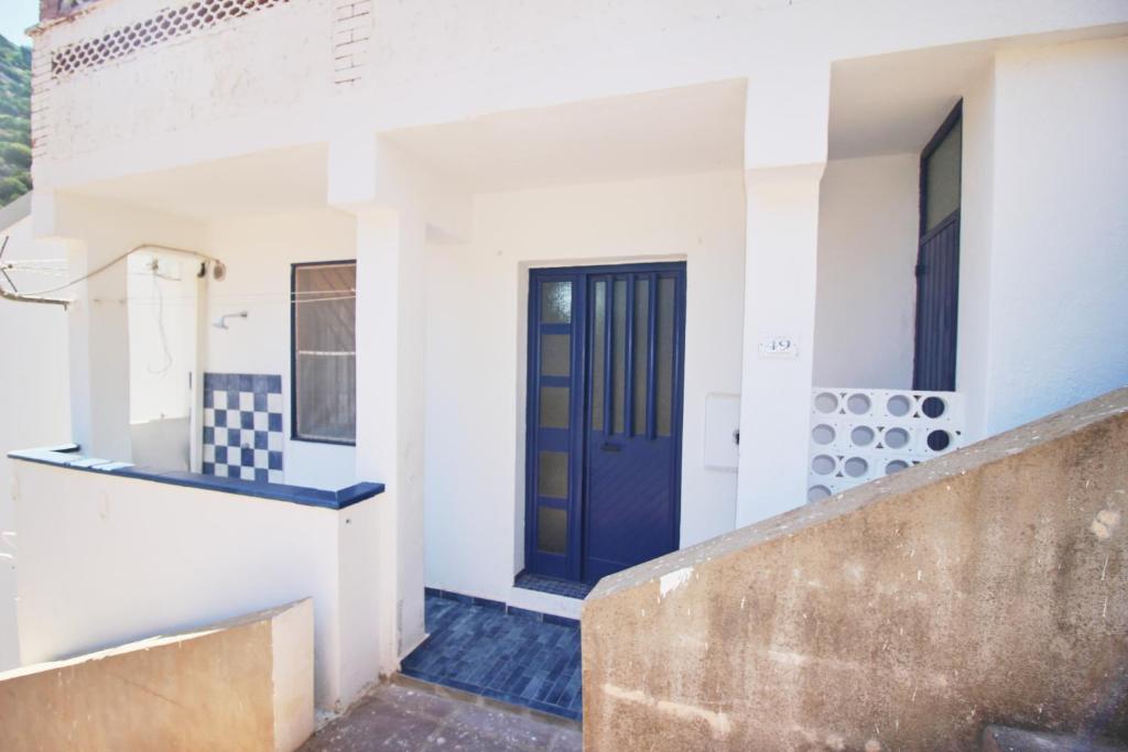 a house with a blue door on a building at Appartamento Buggerru Blue Nest in Buggerru
