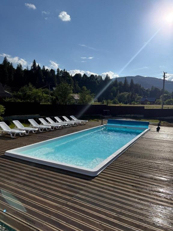 a large swimming pool with lounge chairs on a deck at Kozarik in Mykulychyn
