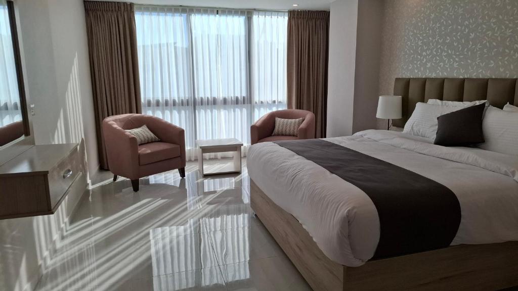 ein Schlafzimmer mit einem großen Bett und zwei Stühlen in der Unterkunft فندق جواهر العبدلي - Jawaher Hotel in Amman