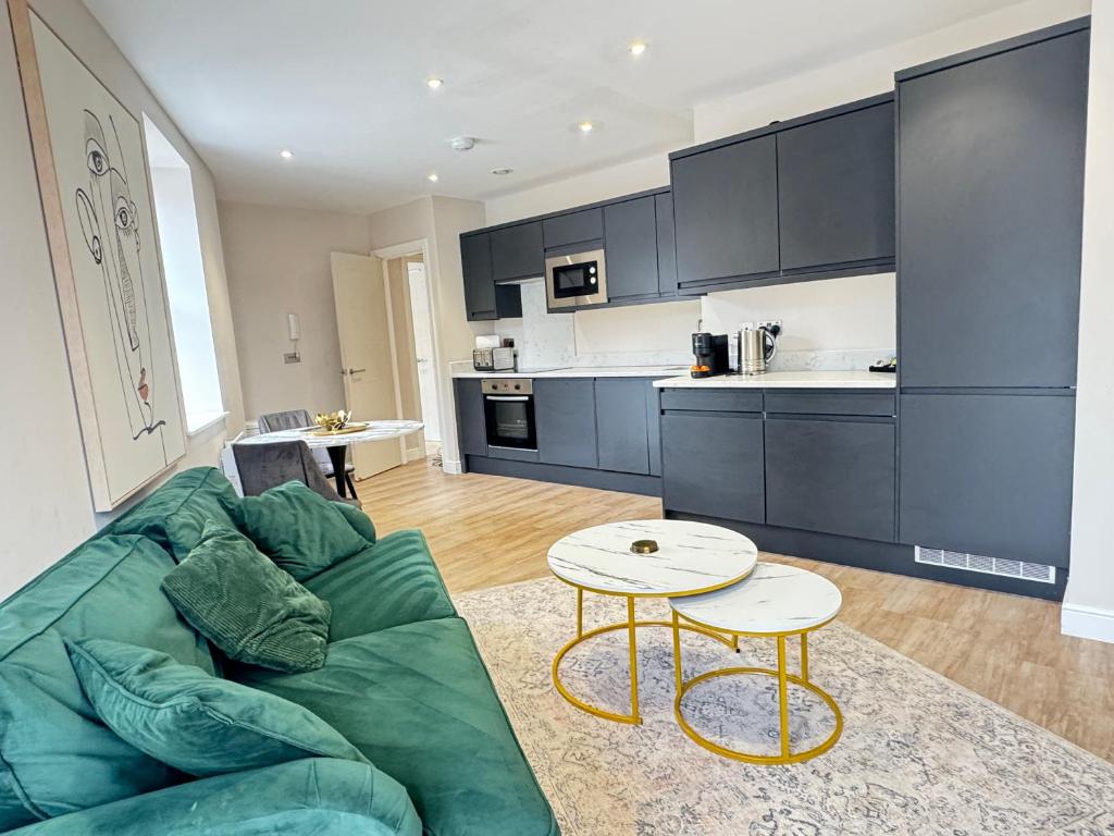 a living room with a green couch and a table at Stylish City Centre Flat - Walk to Trinity & Station in Leeds