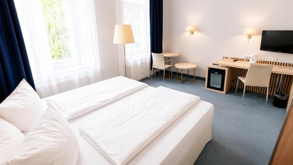 pokój hotelowy z białym łóżkiem i biurkiem w obiekcie Saigon Blue Hotel w Dreźnie