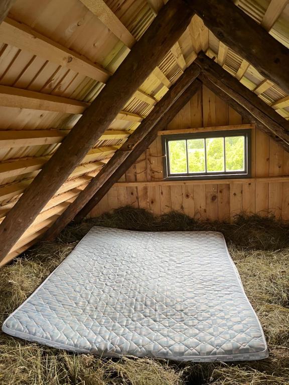 a mattress in the attic of a building with a window at Heinaküün - magamine heinalakas in Pärna