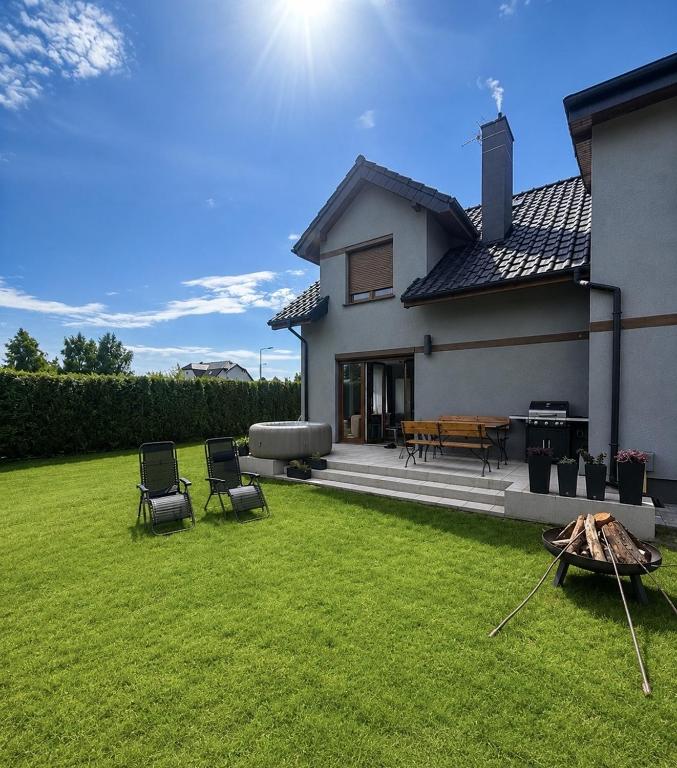 a house with a lawn with two chairs and a table at Morze u Sary - Wrzosowo 361, Dziwnówek in Dziwnówek