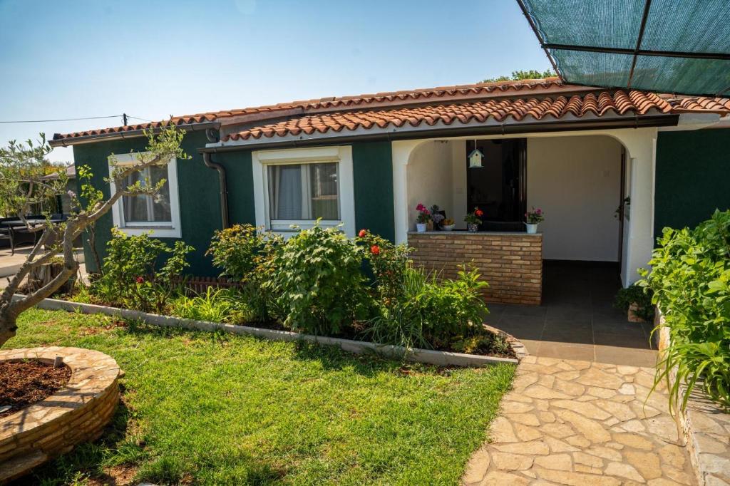 a green house with a porch and a garden at Aria garden house in Loborika