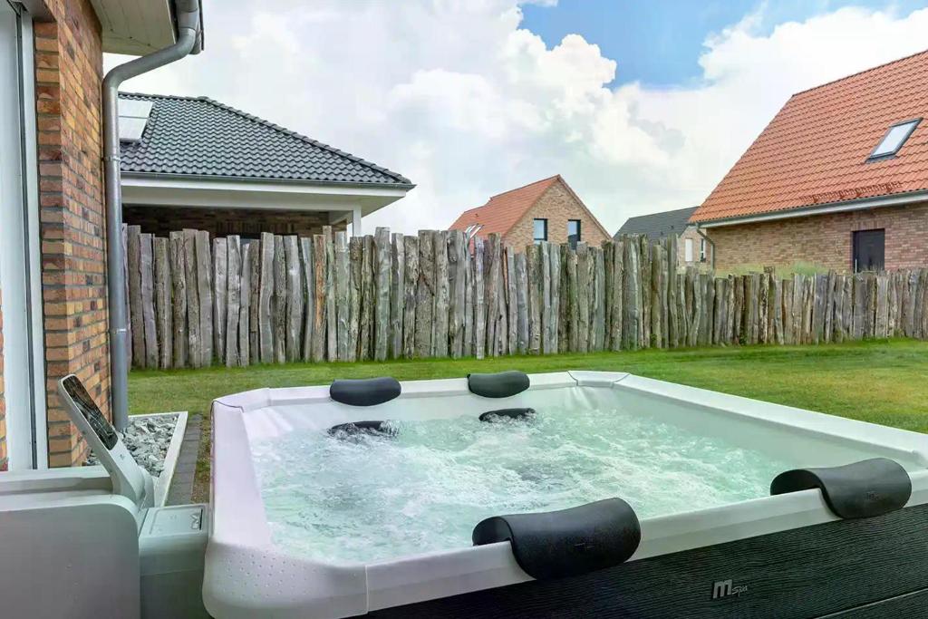 a hot tub in a backyard with a fence at Salz & Seele Das Spa Ferienhaus mit Whirlpool, Sauna & Wallbox in Büsum
