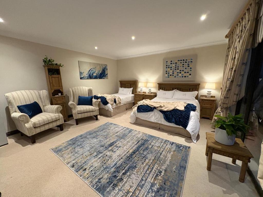 a bedroom with two beds and two chairs in it at Marble on 8 in Rustenburg