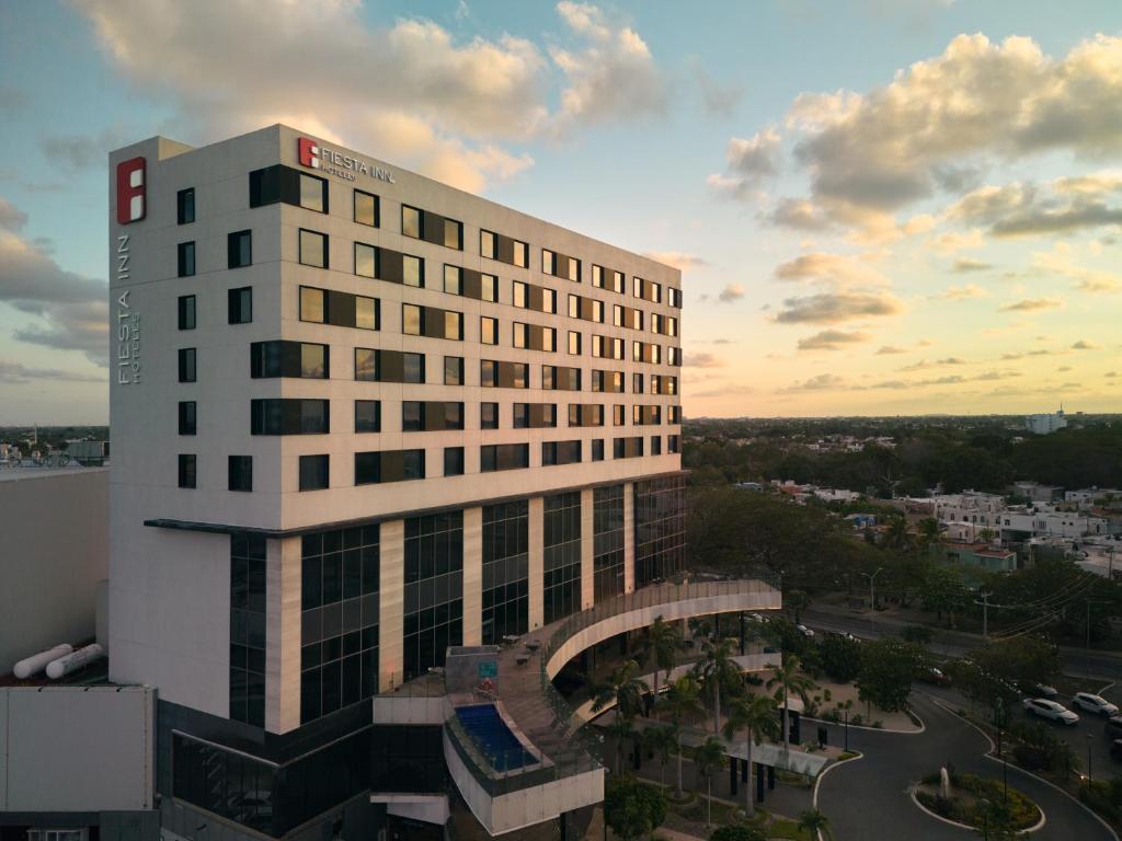 a tall white building with a sunset in the background at Fiesta Inn Mérida Altabrisa in Mérida