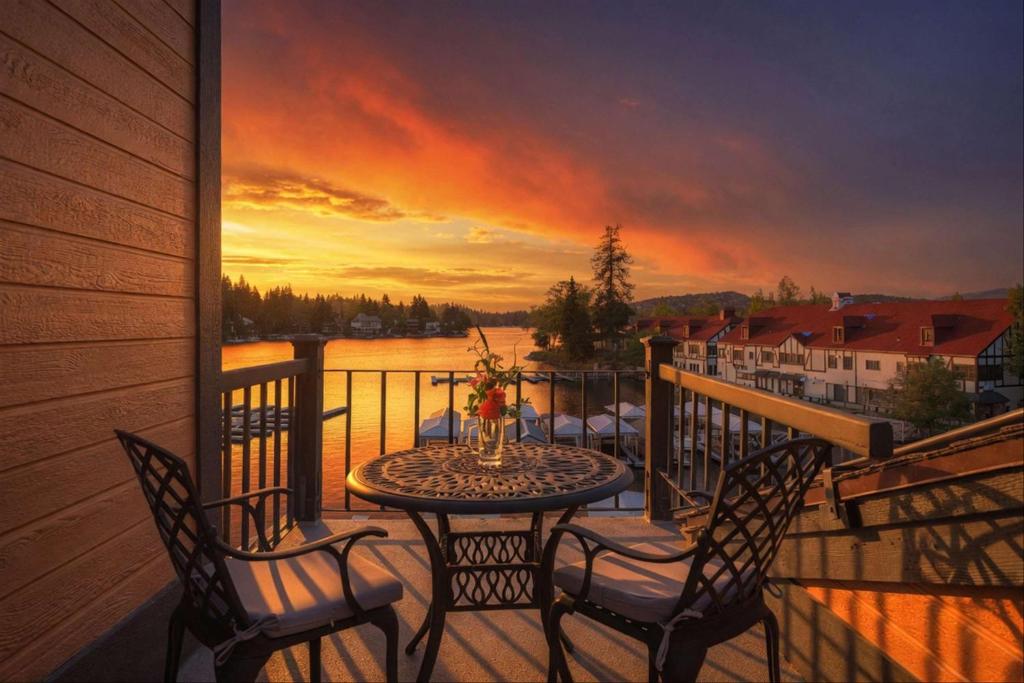 a table and chairs on a balcony with a sunset at Village Lakefront Paradise in Lake Arrowhead