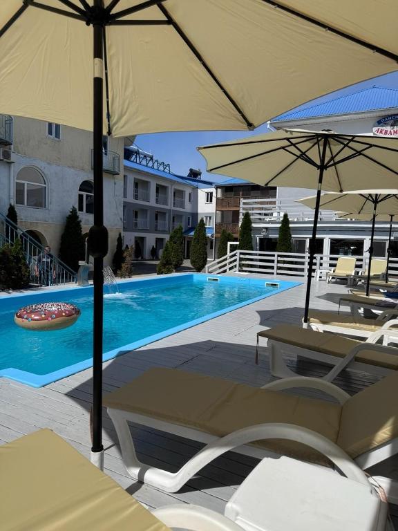 a swimming pool with chairs and umbrellas next to a building at Aquamarin in Zatoka