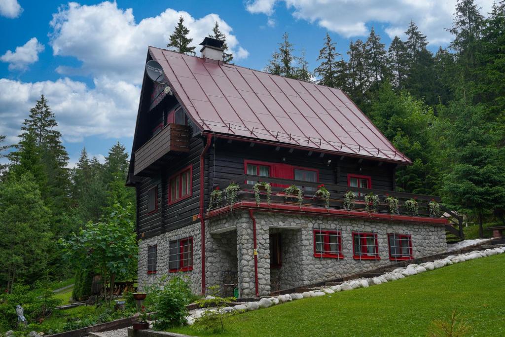 a house with a red roof and red windows at Chata Partizán in Liptovský Ján