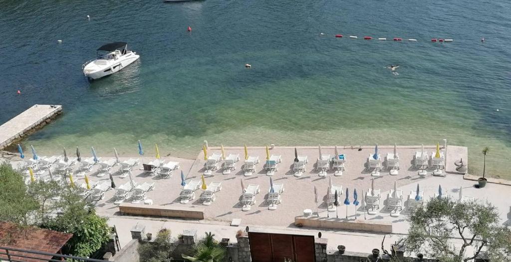 a boat in the water next to a beach with chairs at Obala in Tivat