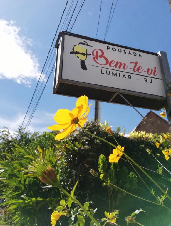 a sign for a restaurant with a yellow flower at Pousada Bem Te Vi Lumiar in Lumiar