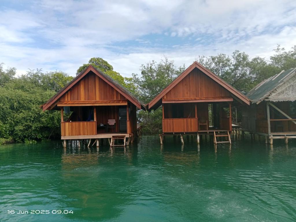 two huts on stilts in a body of water at Lagoon Homestay in Keruo