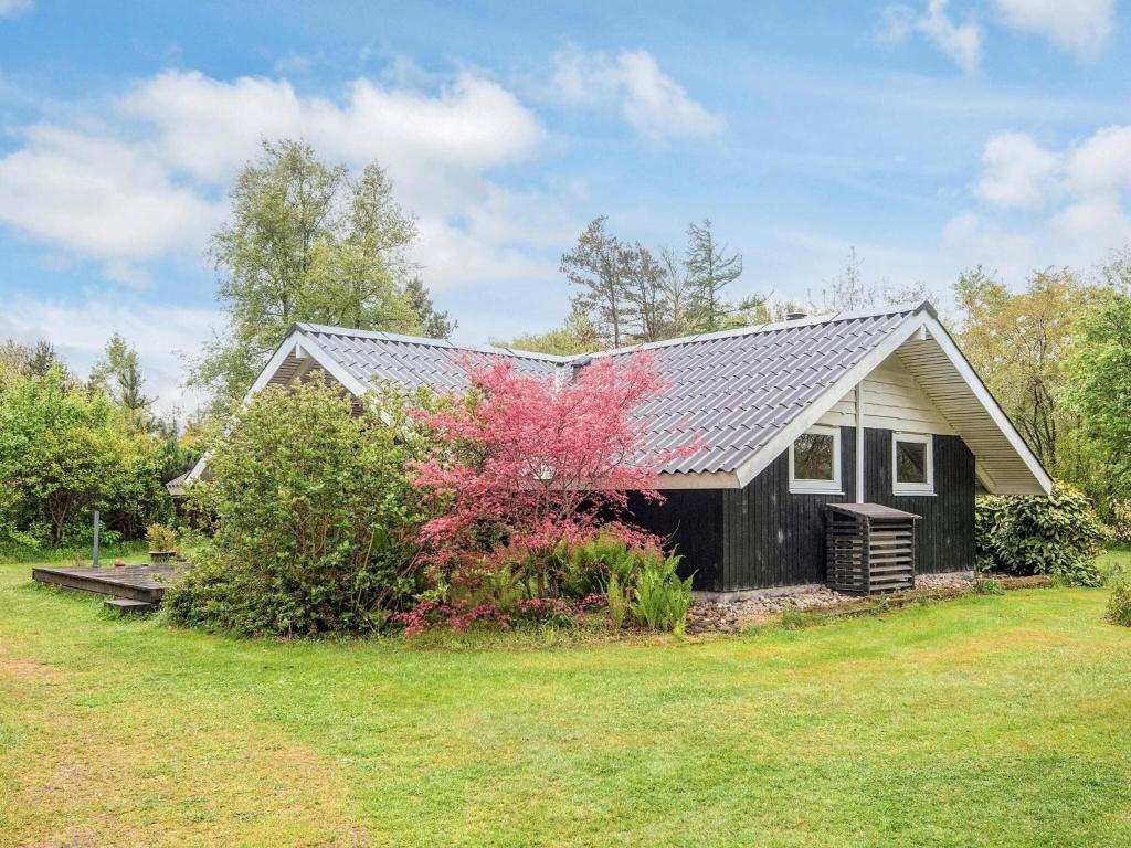 a small house with a red tree in front of it at 6 person holiday home in Oksbøl in Oksbøl