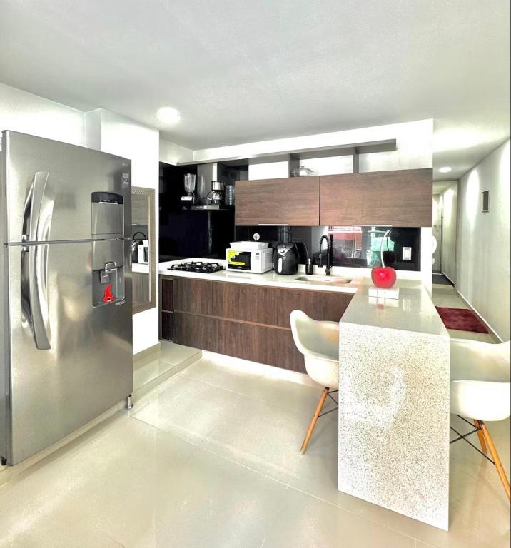 a kitchen with a stainless steel refrigerator and a table at Apartamento Tranquilo y Acogedor in Sabaneta