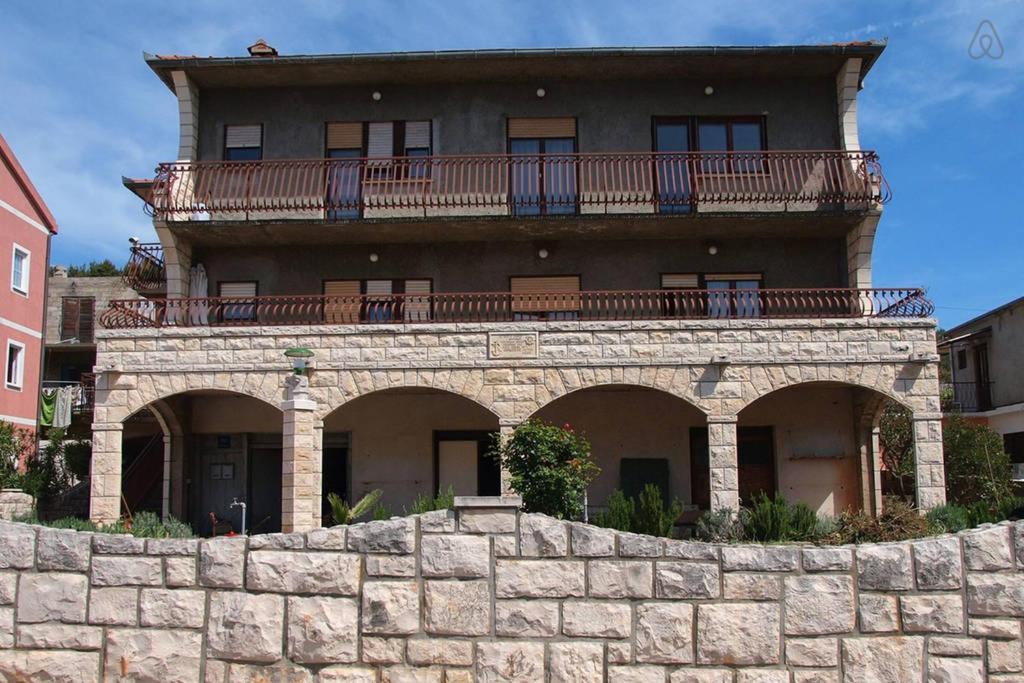 - un grand bâtiment avec un balcon au-dessus d'un mur en pierre dans l'établissement Studio Rade, à Stari Grad