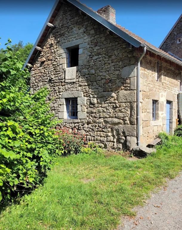 a stone building with two windows on the side of it at La Petite Ferme d'Autrefois in Saint-Georges-Nigremont