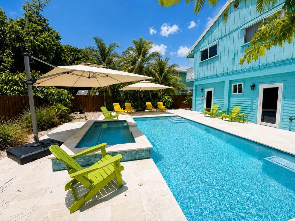 a swimming pool with chairs and an umbrella at Key Largo Home with Spa and Pool in Key Largo