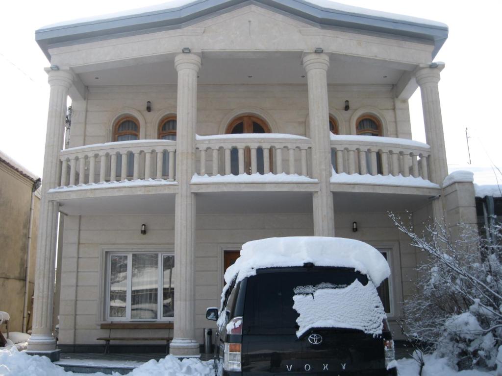 ein Van vor einem schneebedeckten Haus geparkt in der Unterkunft Hotel Elegant in Kutaissi