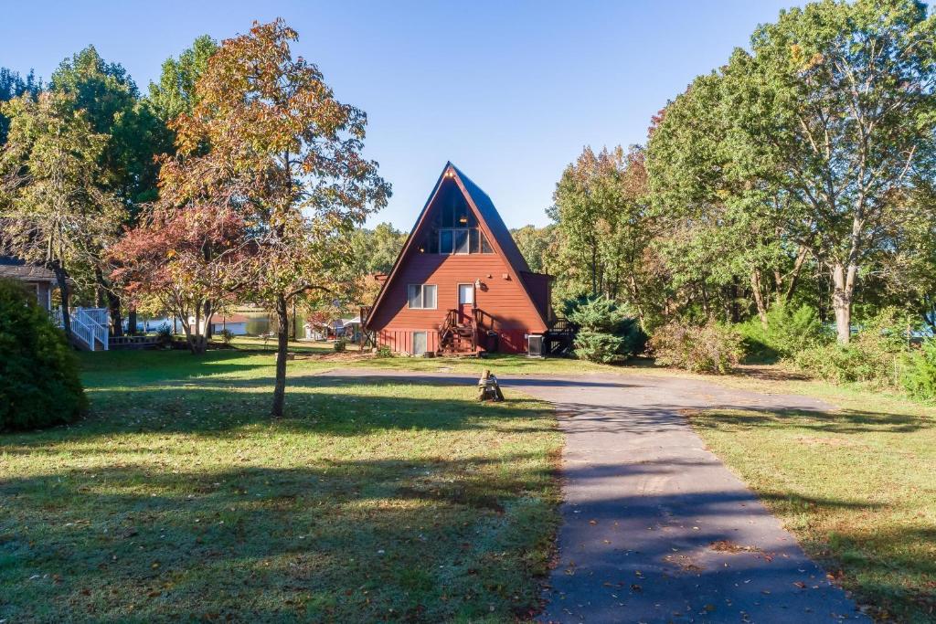 a dog sitting in front of a house at Charming, lakefront A-frame with private dock, lakeside gazebo, spacious deck in Bumpass