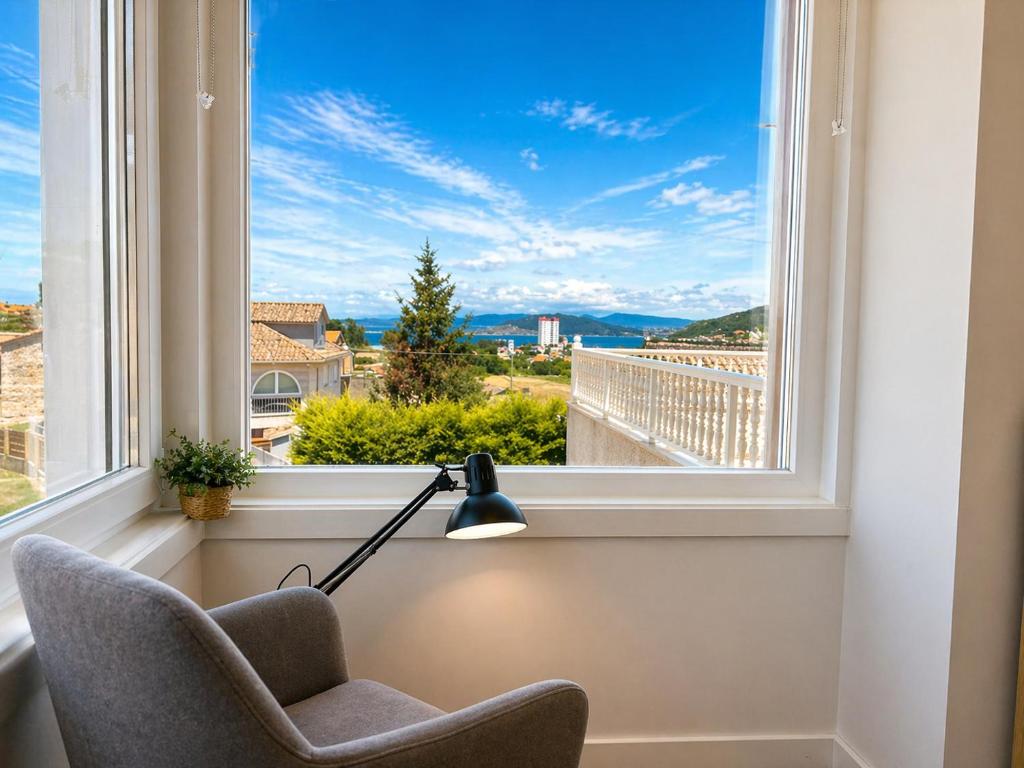 a room with a window with a chair and a lamp at Holibai Portaliña, Mar y Montaña, Baiona in Baiona